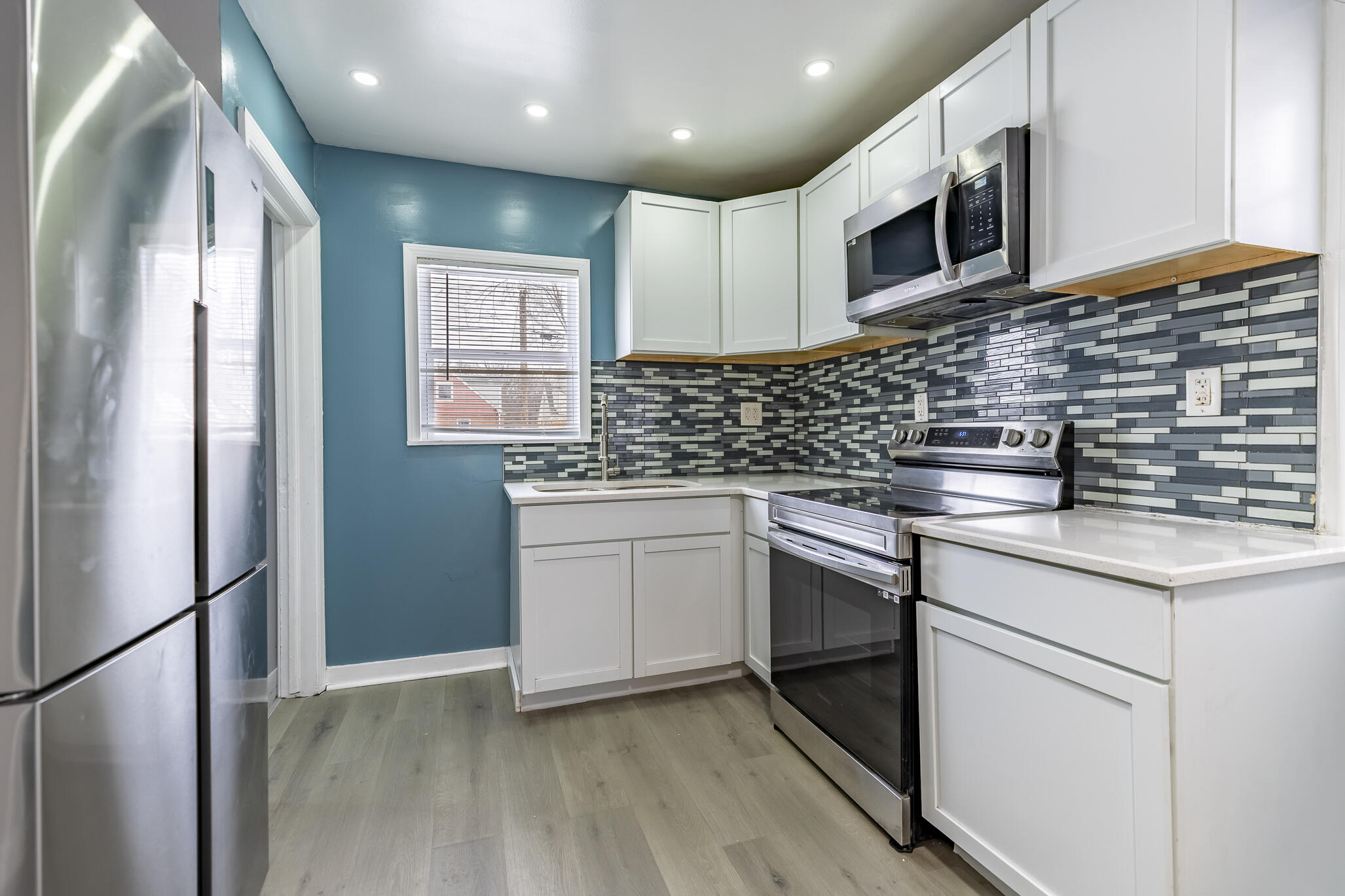 4601 Buchanan Street Gary, IN 46408 - Photo 11 of 27 a kitchen with stainless steel appliances granite countertop white cabinets a sink a stove a refrigerator and a microwave