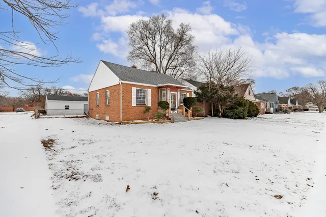 a front view of a house with a yard covered in snow