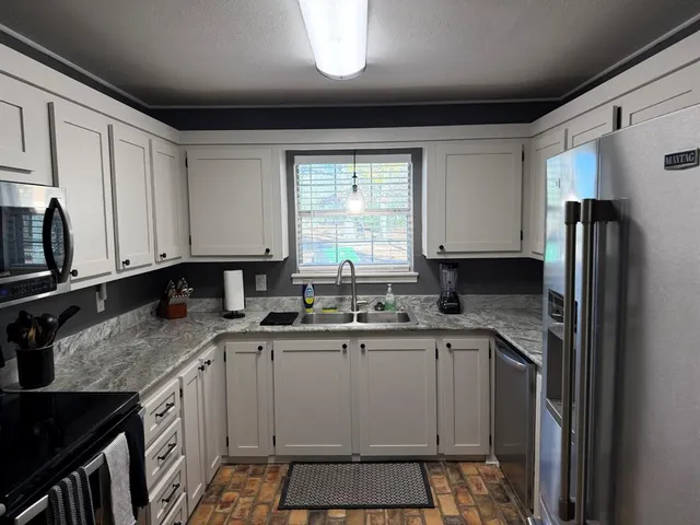 a kitchen with stainless steel appliances granite countertop a sink stove and refrigerator