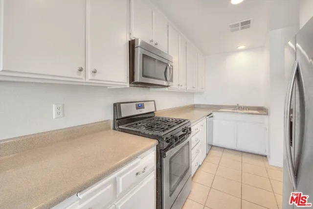 a kitchen with granite countertop white cabinets and stainless steel appliances
