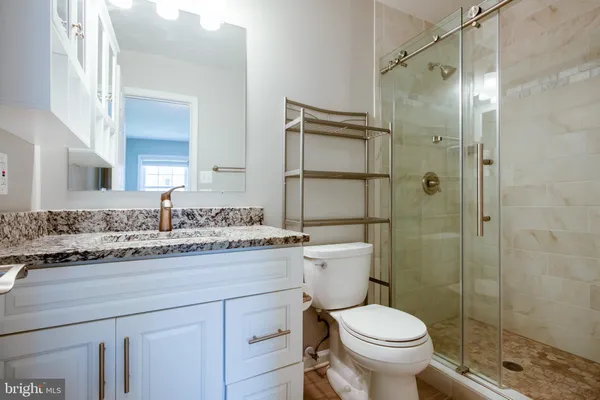a bathroom with a granite countertop toilet sink shower and mirror