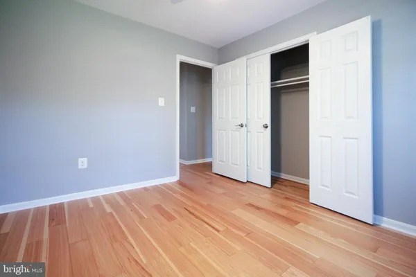 a view of an empty room with wooden floor and closet