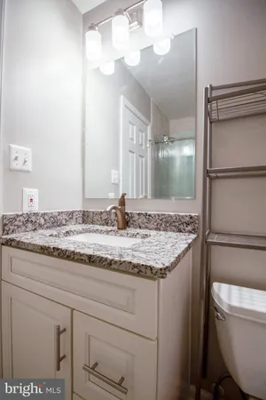 a bathroom with a granite countertop sink a toilet and a mirror
