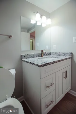 a bathroom with a granite countertop toilet sink and mirror