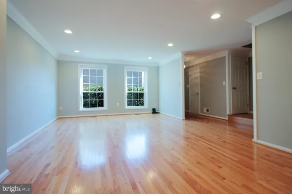 a view of an empty room with wooden floor and windows