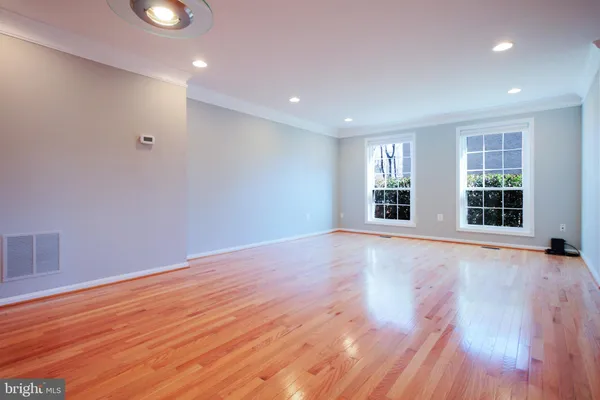 a view of an empty room with wooden floor and windows