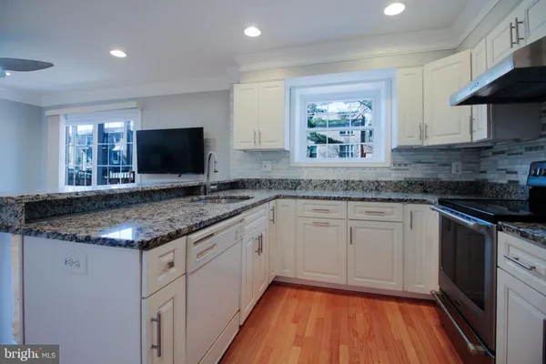 a kitchen with granite countertop stainless steel appliances a sink stove and cabinets