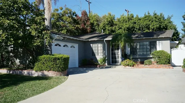a front view of a house with a yard and potted plants