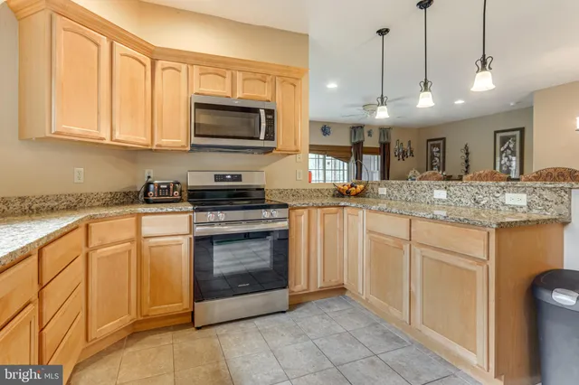 a kitchen with stainless steel appliances granite countertop a stove a sink and a microwave