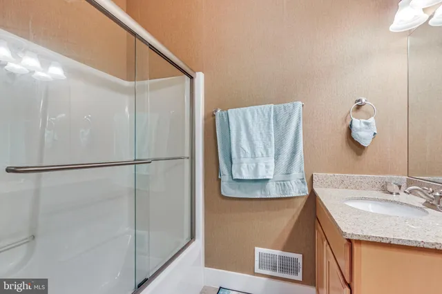 a bathroom with a granite countertop shower sink vanity and mirror