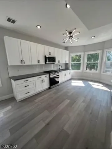 a kitchen with stainless steel appliances a stove top oven a sink a window and white cabinets