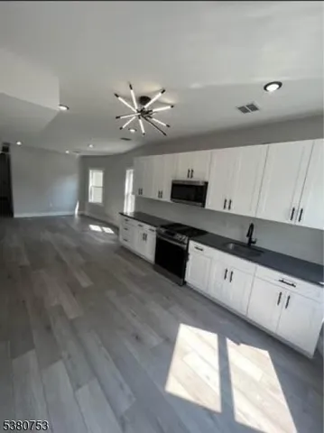 a large kitchen with stainless steel appliances kitchen island granite countertop a stove a sink and white cabinets