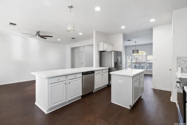 a kitchen that has a lot of white cabinets and wooden floor