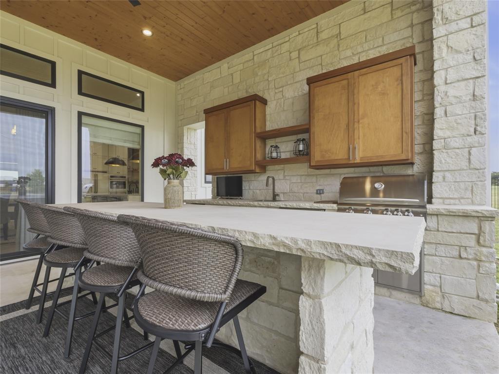 4211 Azalea Way Midlothian, TX 76065 - Photo 38 of 39 Outdoor kitchen featuring a stone-clad island with a light-toned countertop, integrated stainless steel grill, and built-in cabinetry
