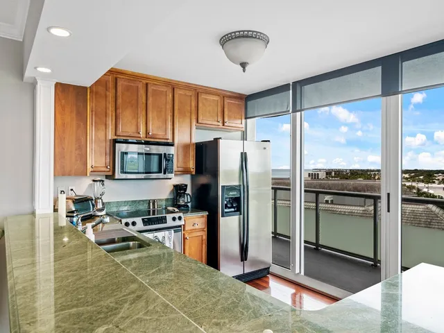 a kitchen with stainless steel appliances granite countertop a refrigerator a stove and a sink with wooden floor