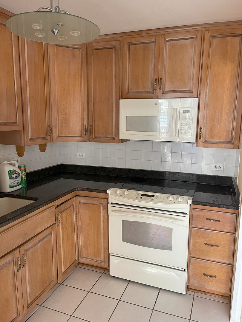 6301 North Sheridan Road, Unit 22F Chicago, IL 60660 - Photo 7 of 11 a kitchen with granite countertop white cabinets and white appliances