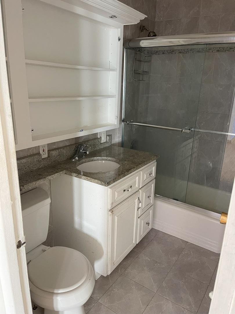 6301 North Sheridan Road, Unit 22F Chicago, IL 60660 - Photo 10 of 11 a bathroom with a granite countertop sink toilet and shower