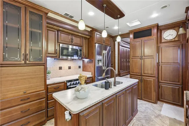 a kitchen with stainless steel appliances kitchen island granite countertop a sink and refrigerator