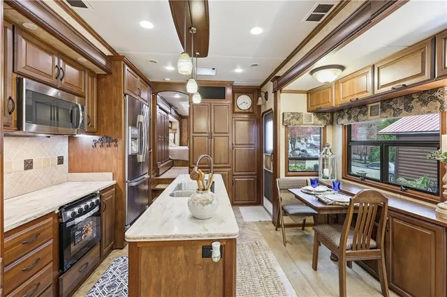 a open kitchen with stainless steel appliances kitchen island granite countertop a table chairs in it and wooden floors