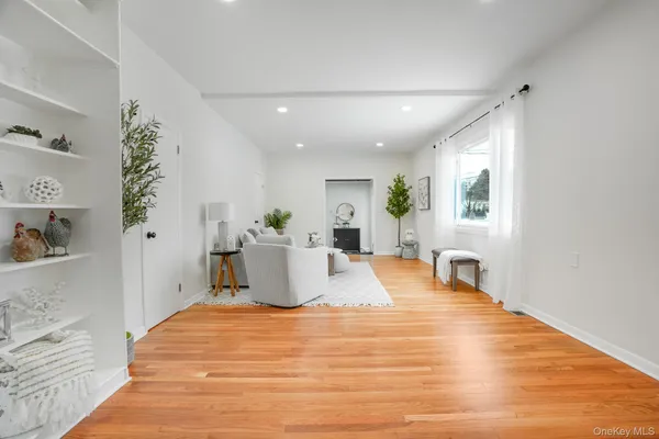 a large white kitchen with wooden floor and potted plant