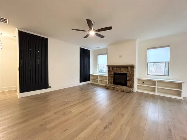 an empty room with wooden floor fireplace and windows