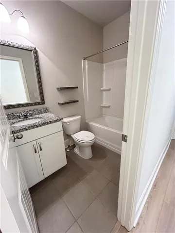 a bathroom with a granite countertop sink a toilet a mirror and vanity