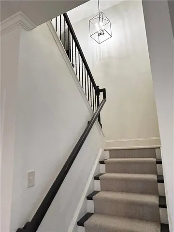 a view of staircase with railing and white walls