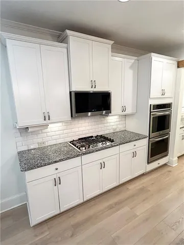 a kitchen with granite countertop a stove a sink and a microwave