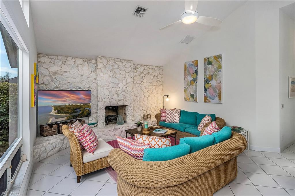 720 Turkey Oak Lane Naples, FL 34108 - Photo 27 of 31 a living room with furniture a fireplace and a flat screen tv