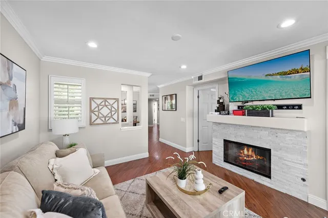 a living room with furniture kitchen view and a wooden floor