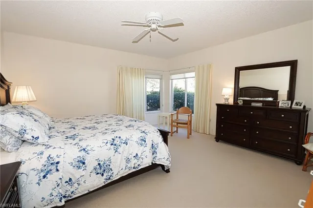 a bedroom with a bed dresser and two windows