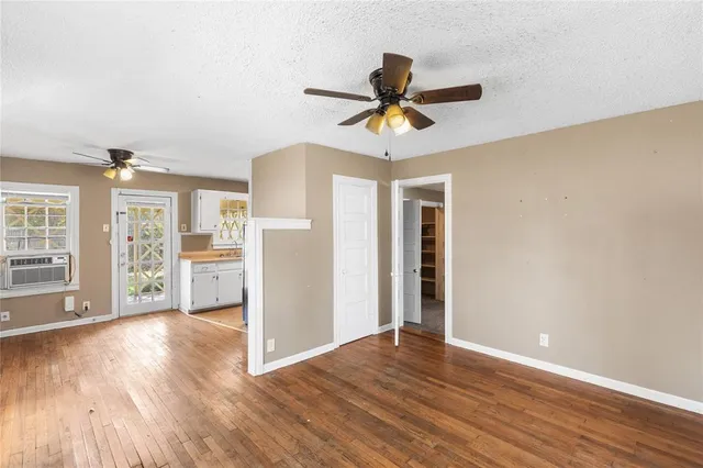 a view of a big room with wooden floor a ceiling fan and windows