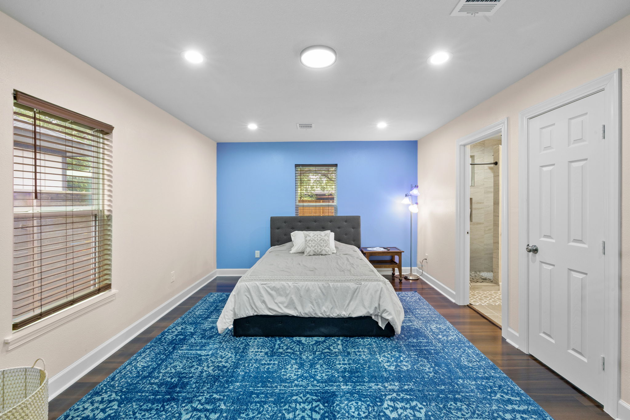 907 East 53rd Street Austin, TX 78751 - Photo 26 of 36 Recessed lighting illuminates this inviting bedroom featuring rich hardwood flooring and a serene blue accent wall.