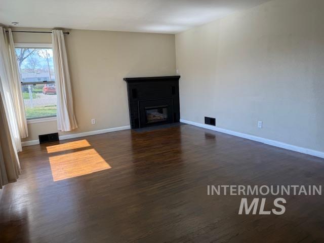 1139 Webster Street Clarkston, WA 99403 - Photo 7 of 34 Unfurnished living room featuring dark wood-type flooring and a fireplace with flush hearth