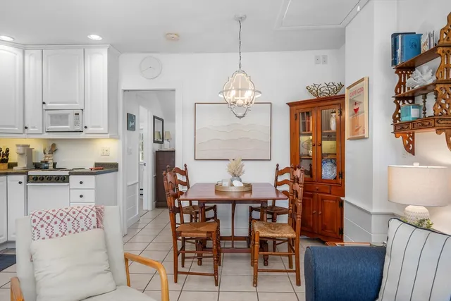 a dining room with wooden floor a chandelier a glass table and chairs