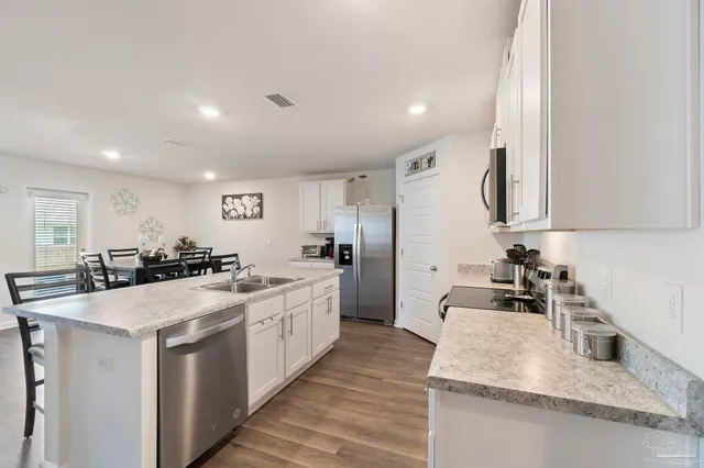 a large white kitchen with stainless steel appliances granite countertop a sink stove and refrigerator
