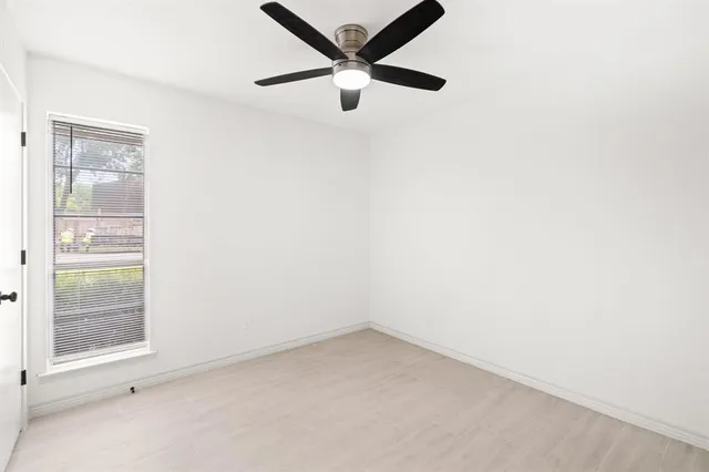 an empty room with a window and a fan