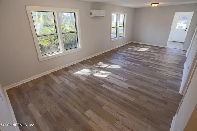 a view of empty room with window and wooden floor
