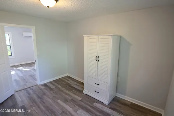 an empty room with wooden floor cabinet and windows
