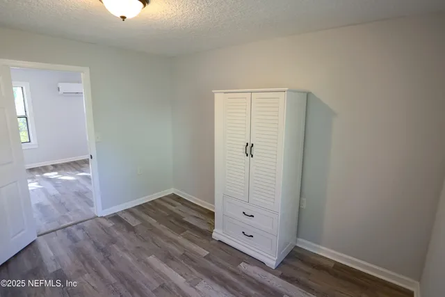 an empty room with wooden floor cabinet and windows