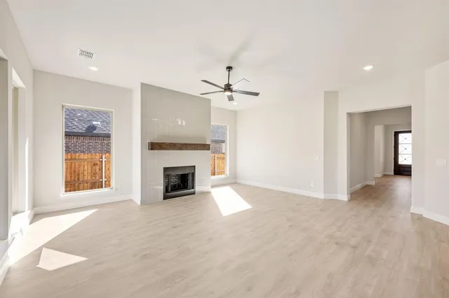 a view of a livingroom with a fireplace a ceiling fan and windows