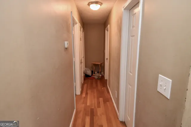 a view of a hallway with wooden floor and a bathroom
