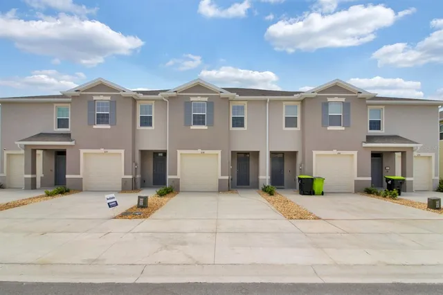 a view of a white house with large windows and a table and chairs