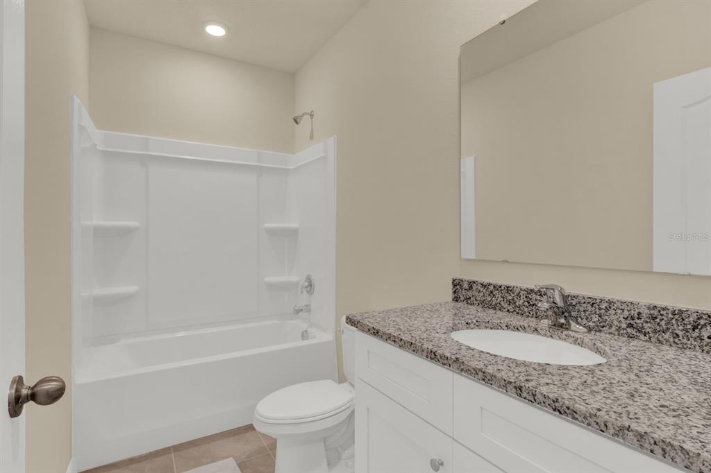 1238 Lido Drive Howey-in-the-Hills, FL 34737 - Photo 25 of 27 a bathroom with a granite countertop sink toilet and shower