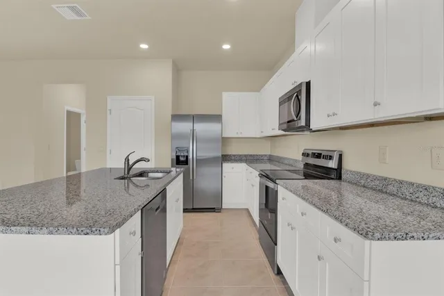 a kitchen with stainless steel appliances granite countertop a sink a stove and a refrigerator