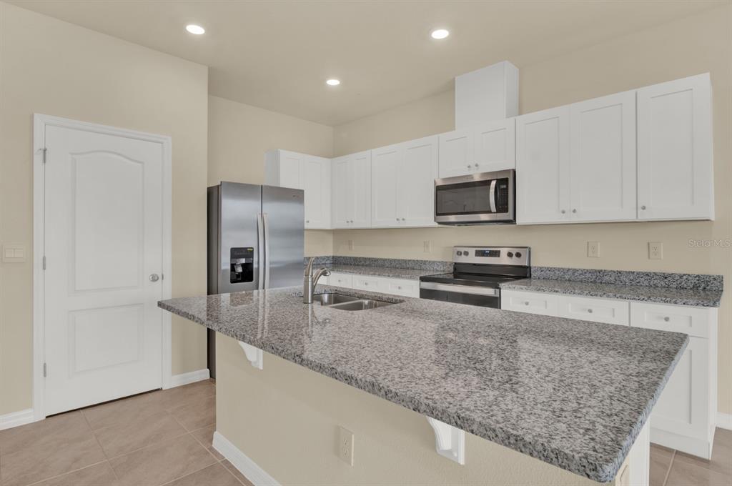 1238 Lido Drive Howey-in-the-Hills, FL 34737 - Photo 10 of 27 a kitchen with stainless steel appliances granite countertop a sink a stove and a refrigerator with white cabinets