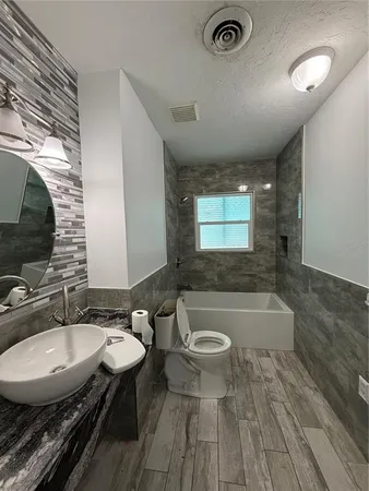 a bathroom with a granite countertop sink a mirror and a bathtub