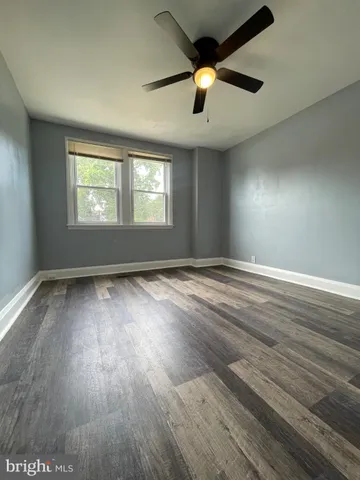 an empty room with wooden floor ceiling fan and windows