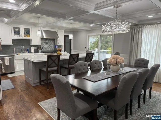 a dining room with wooden floor a chandelier a wooden table and chairs