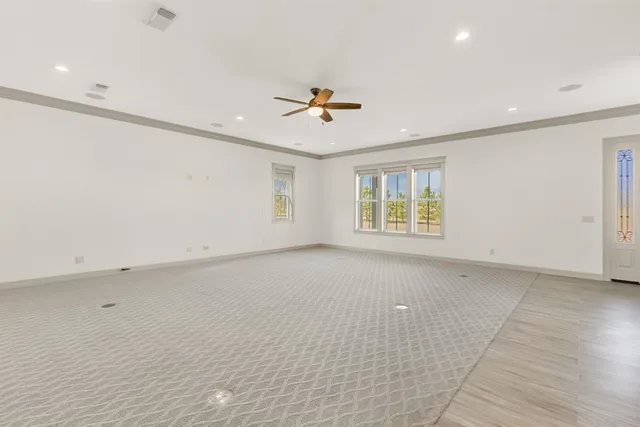 an empty room with chandelier fan and windows